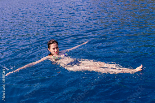 Young woman swimming in deep tranquil turquoise water in open Mediterranean sea