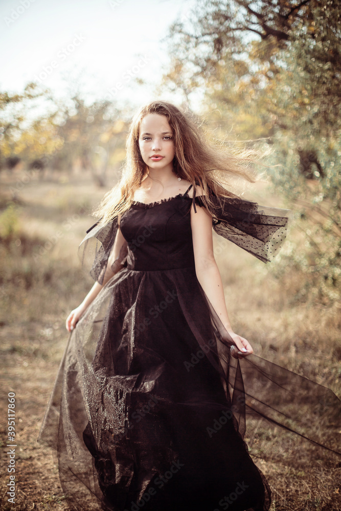 girl stands in the park in autumn in the rays of the setting sun girl stands in the park in autumn in the rays of the setting sun
