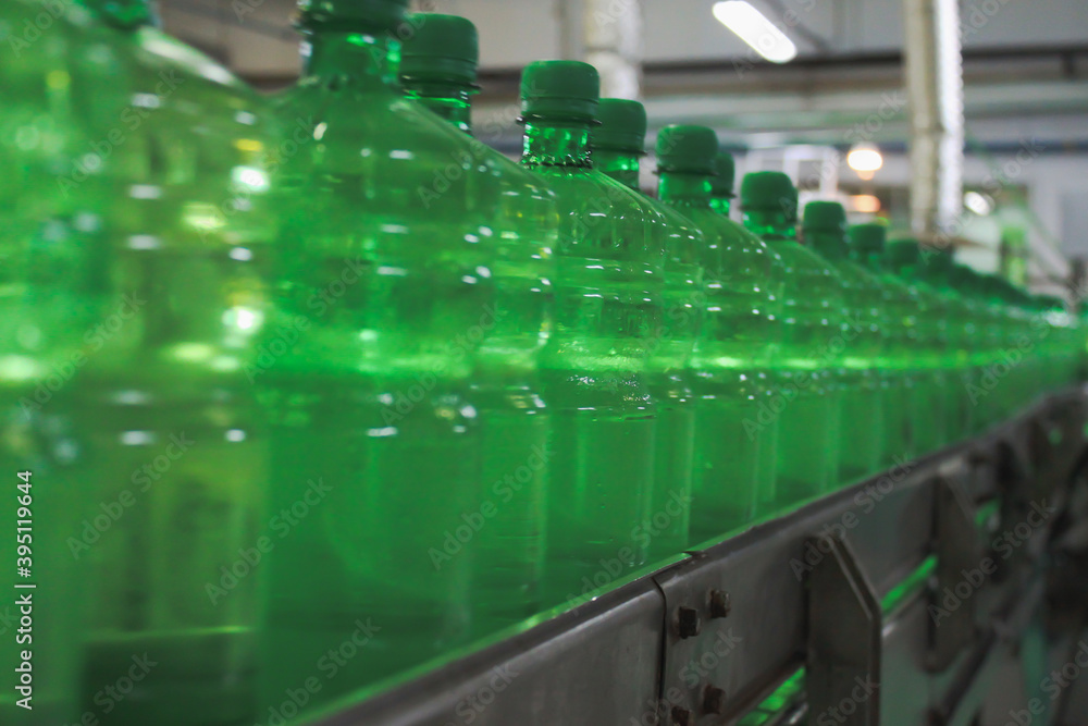 A conveyer belt with green plastic bottles for beverages. Perspective view. concept of producing clean bottled water