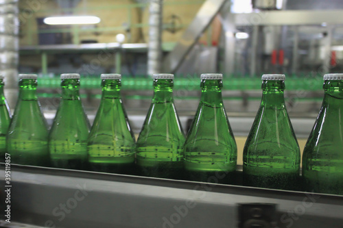 An automatic conveyer belt with green glass bottles for beverages. Concept of producing clean bottled water