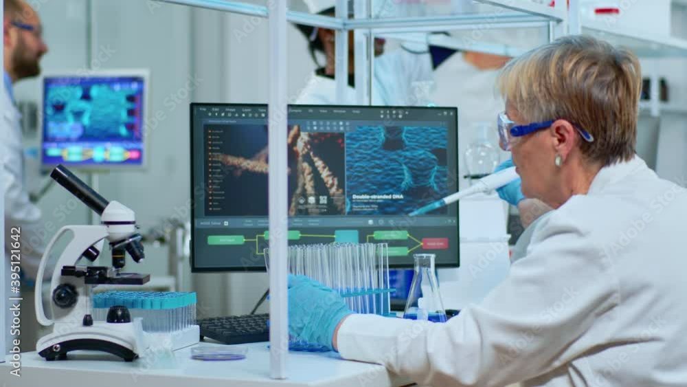 Elderly research scientist using micropipette filling test tubes in ...