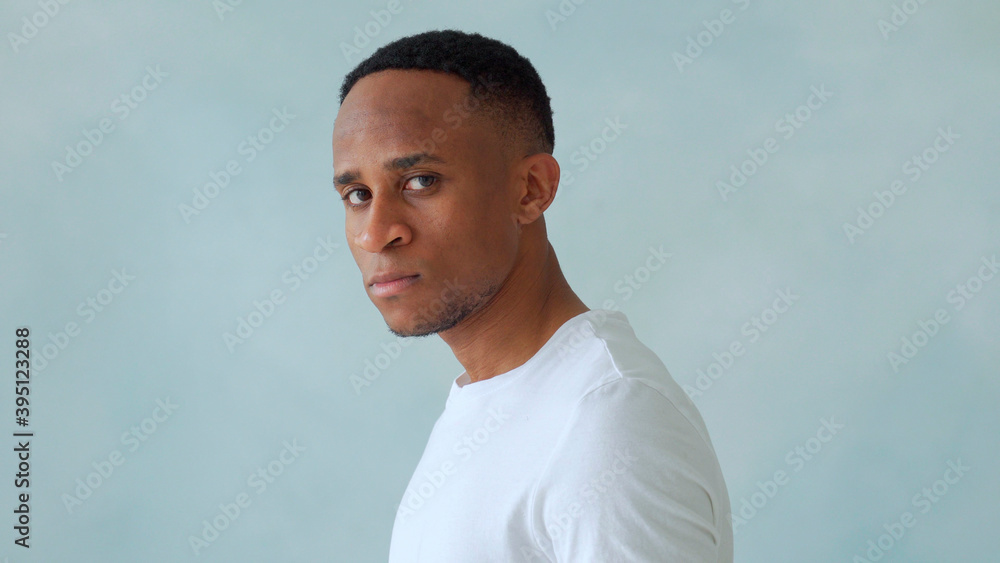 Thinking black Afro American man with serious expression looking with eyes directly into camera while posing against light studio wall. Thinking black Afro American man with serious expression looking with eyes directly into camera while posing against light studio wall.