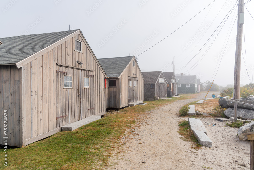 Row of wooden fisherman huts along a sandy coastal path on a foggy autumn morning. Seacoast region, NH, USA.