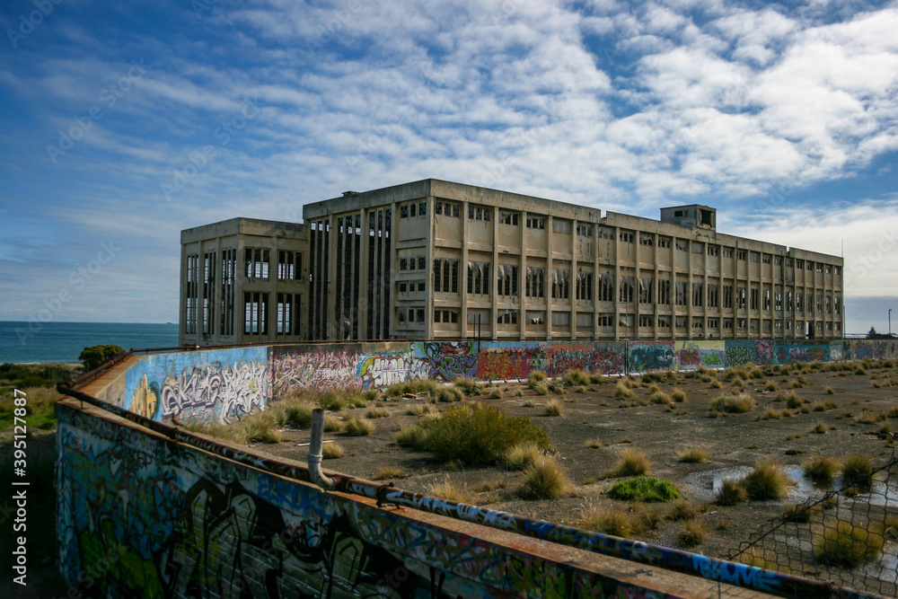 Obraz premium Old Power Station in Fremantle with graffiti on sunny day with blue sky and some clouds, next to the beach, lost places, Perth, Western Australia