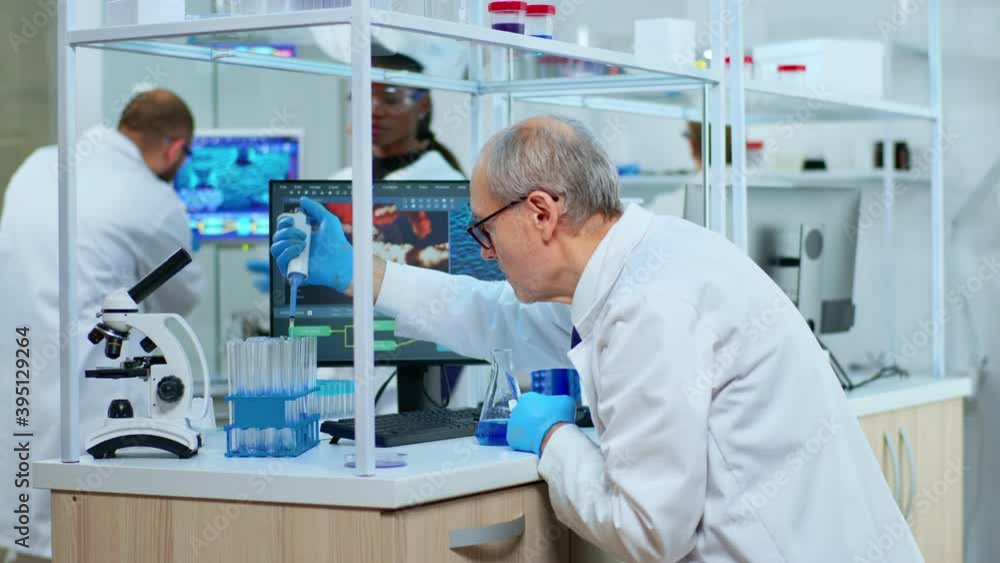 Senior neurologist working at vaccine development in modern equipped laboratory. Multiethnic team examining virus evolution using high tech for research in treatment development against covid19 Senior neurologist working at vaccine development in modern equipped laboratory. Multiethnic team examining virus evolution using high tech for research in treatment development against covid19