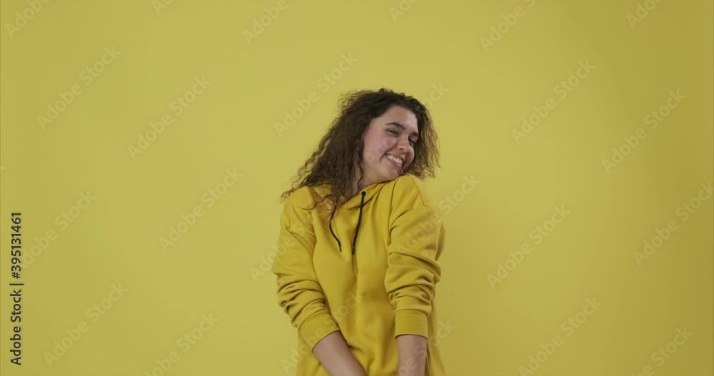 Smiling woman feeling shy and giving flying kiss over yellow background Smiling woman feeling shy and giving flying kiss over yellow background