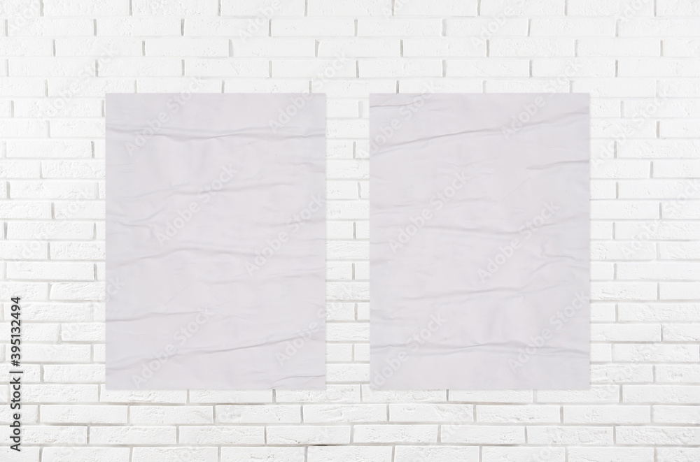 Blank creased posters on white brick wall. Mockup for design Stock