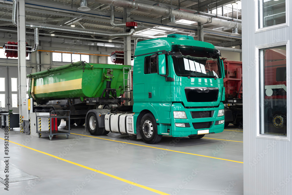 Trucks being repaired in a larger garage. Service maintenance of trucks and cars, diagnostics, car service. Car service, logistics and cargo transportation concept