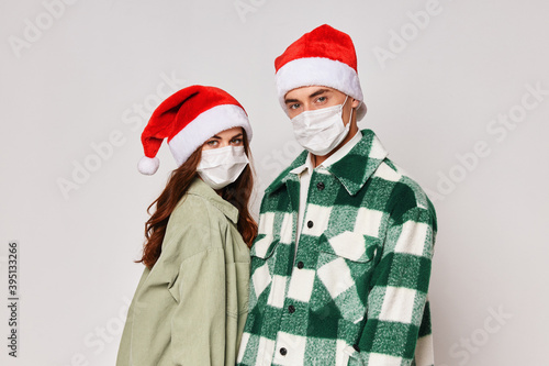 Man and woman in medical masks Christmas hats holiday gray background