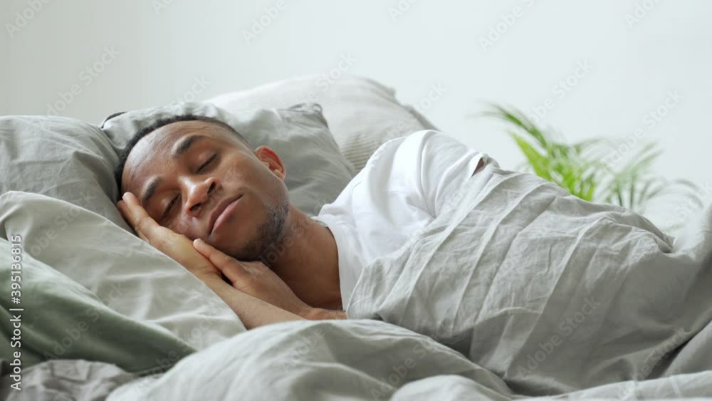 Young african-american man sleeping in bed at home Young african-american man sleeping in bed at home