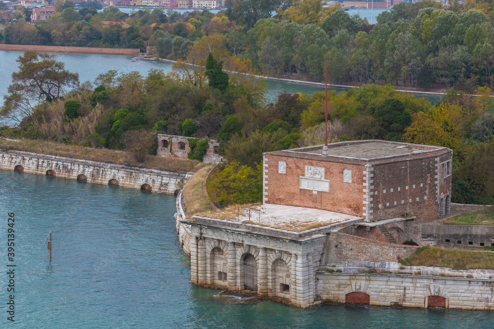 Sant'Andrea Fort in the Venice lagoon, surrounded by trees in autumn colors, Italy
