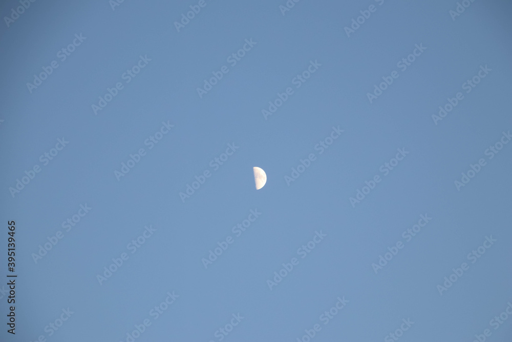 Half moon during day time on a blue sky. Copy space. Half moon during day time on a blue sky. Copy space.