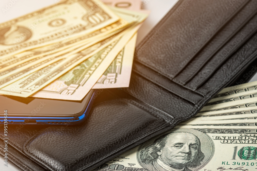 Black leather wallet with money and a mobile phone. Black leather wallet with money and a mobile phone.