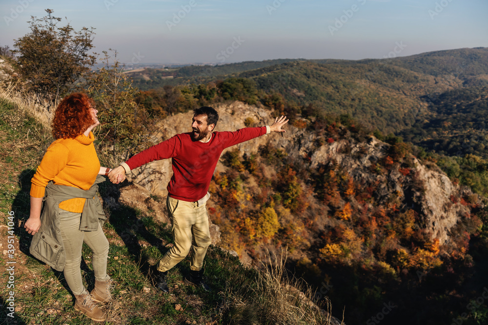 Young happy smiling couple in love spending weekend in nature. Couple holding hands and enjoying beautiful nature on a sunny autumn day.