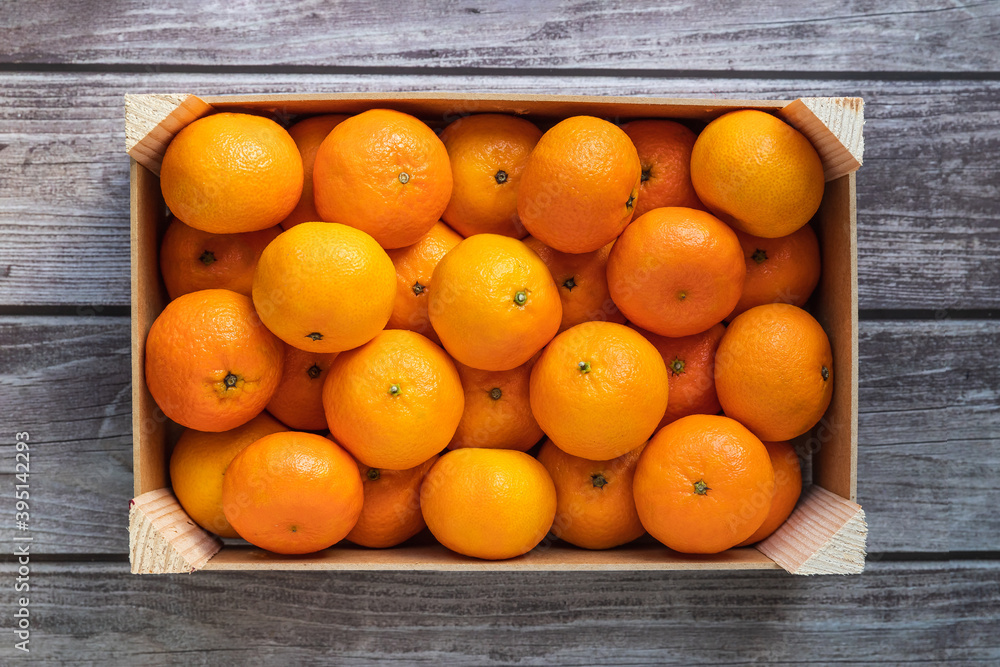 a crate with ripe orange tangerines on a wooden table top view
