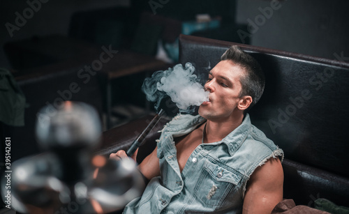 A man of European appearance exhales smoke in the hookah bar. photo