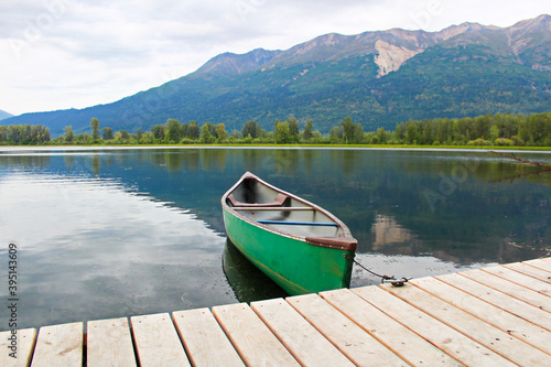 A canoe tied to a dock with mountains in the background