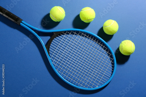 Tennis racket and balls on blue background, flat lay. Sports equipment