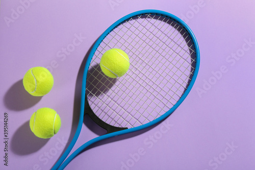 Tennis racket and balls on violet background, flat lay. Sports equipment © New Africa