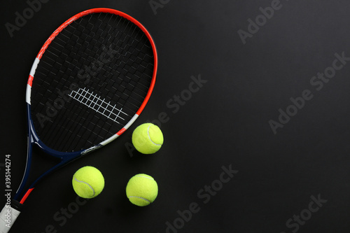 Tennis racket and balls on black background, flat lay. Space for text © New Africa
