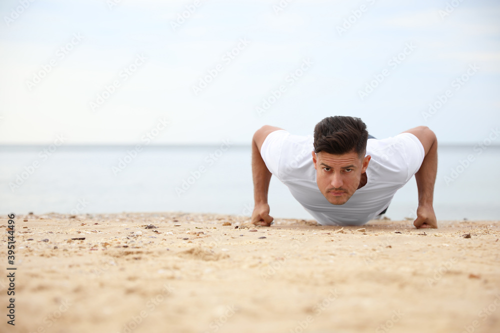 Muscular man doing push up on beach, space for text. Body training Muscular man doing push up on beach, space for text. Body training