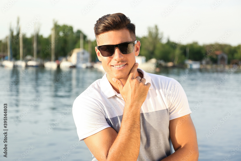 Handsome man wearing stylish sunglasses near river Handsome man wearing stylish sunglasses near river