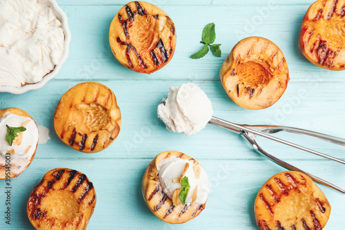 Delicious grilled peaches, ice cream and mint on light blue wooden table, flat lay