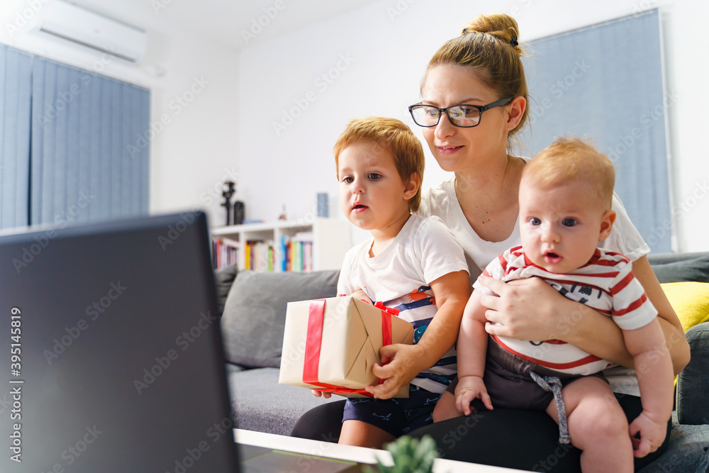 Single mother family woman with two kids having video call at home to celebrate birthday or holiday and share gift online - new normal social distance during covid-19 pandemic concept Single mother family woman with two kids having video call at home to celebrate birthday or holiday and share gift online - new normal social distance during covid-19 pandemic concept