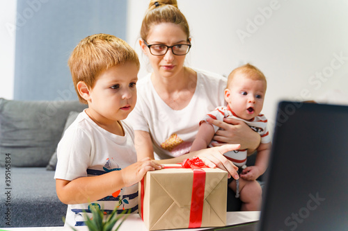 Single mother family woman with two kids having video call at home to celebrate birthday or holiday and share gift online - new normal social distance during covid-19 pandemic concept