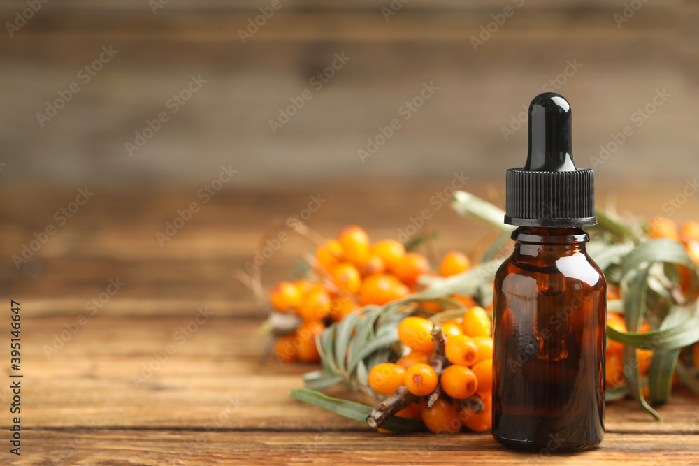 Natural sea buckthorn oil and fresh berries on wooden table. Space for text Natural sea buckthorn oil and fresh berries on wooden table. Space for text