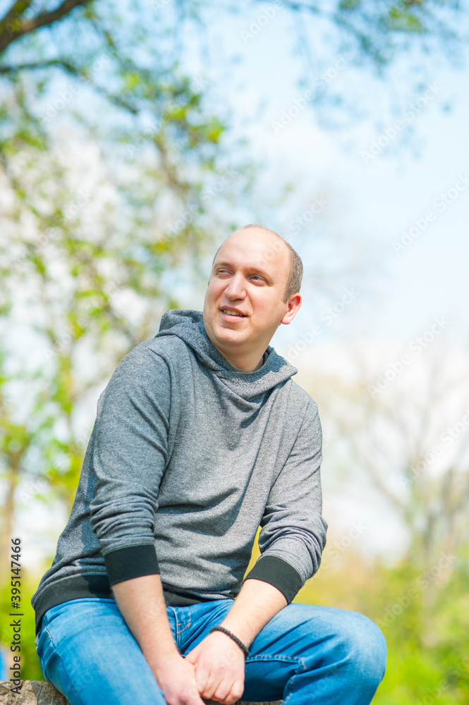 Young man sitting on the stump in the park