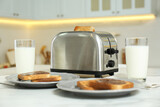 Modern toaster, bread slices with chocolate cream and glasses of milk on white marble table in kitchen