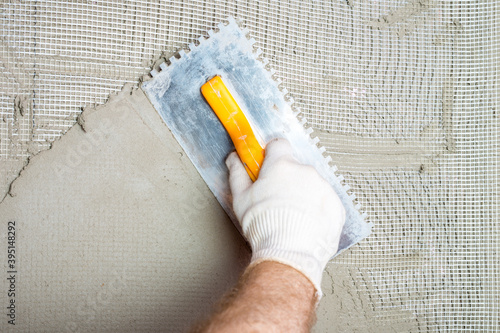 Embedding the fiberglass mesh on the thermal insulation boards and then smoothing the adhesive mortar with a notched trowel. photo