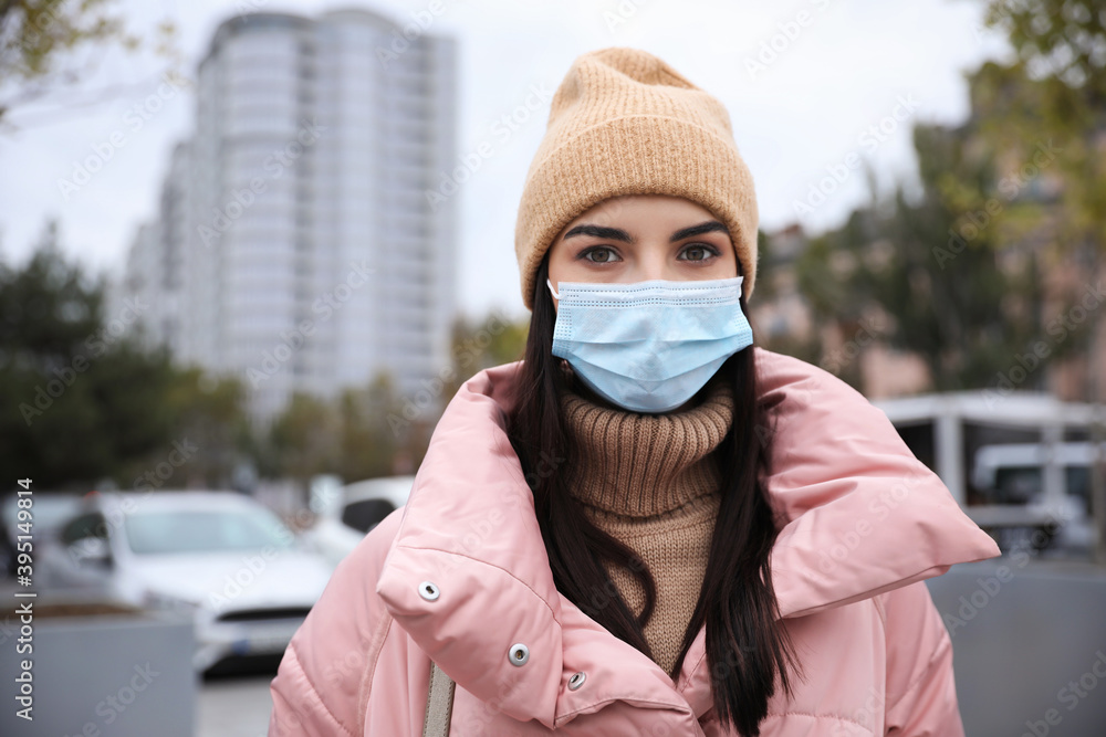 Young woman in medical face mask walking outdoors. Personal protection during COVID-19 pandemic