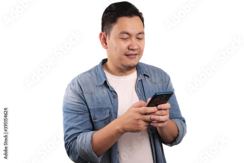 Attractive young Asian man reading texting chatting on his phone, smiling happy laughing expression