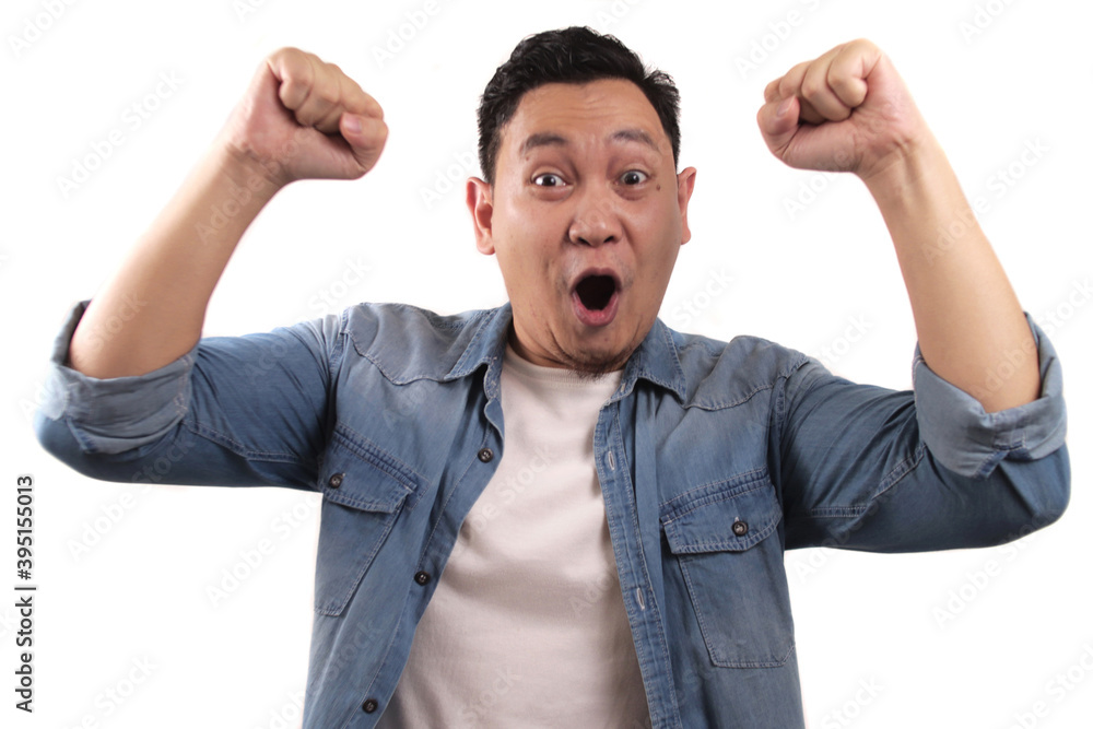Successful young Asian man shows winning gesture, celebrating victory. Hands raised above with expressive omg wow Successful young Asian man shows winning gesture, celebrating victory. Hands raised above with expressive omg wow