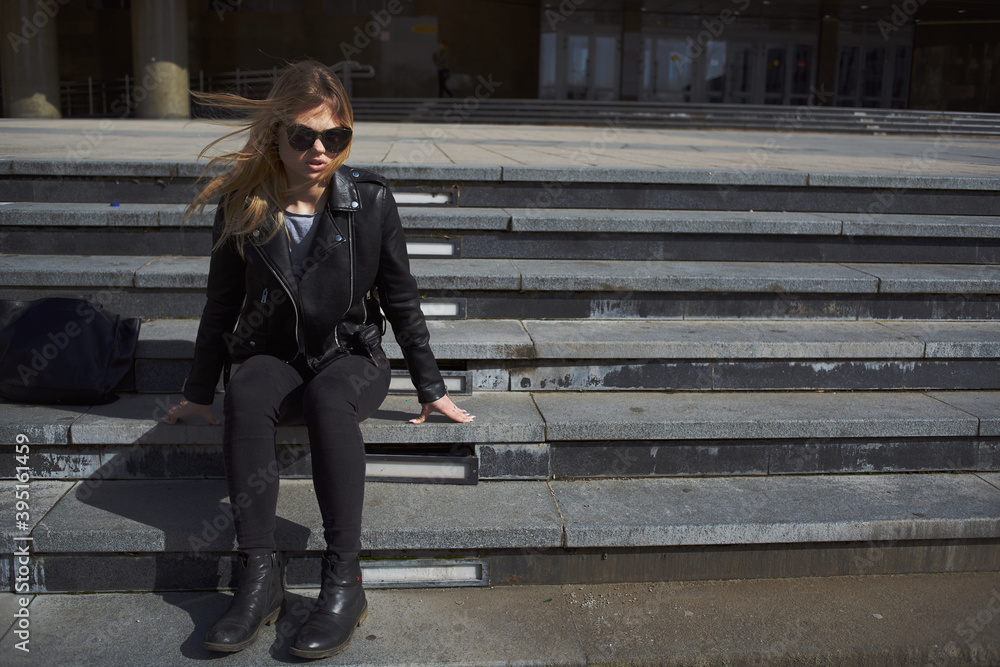 Fototapeta premium Woman model sits on stairs near a building on the street in autumn