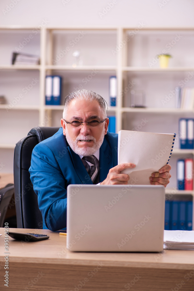 Old male employee unhappy with excessive work in the office Old male employee unhappy with excessive work in the office