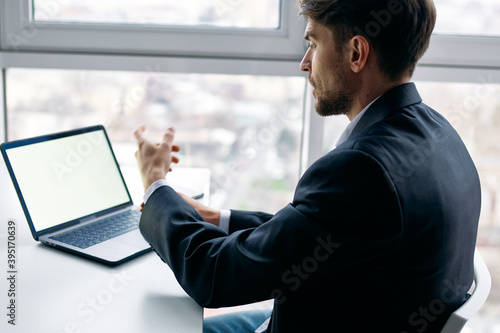 Business man in the office at his desk in front of a laptop communication 