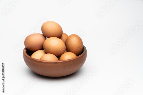 Brown eggs on a clay dish with a white backgrund