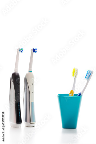 Professional Electric Toothbrushes In Front of Two Manual Tooth Brushes in One Cup On White