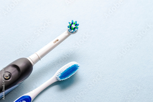 Closeup of Brushing Heads of Professional Electric Toothbrush and Manual Brush on Blue  Background.