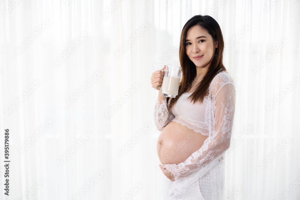 pregnant woman drinking a milk at the window in bedroom pregnant woman drinking a milk at the window in bedroom