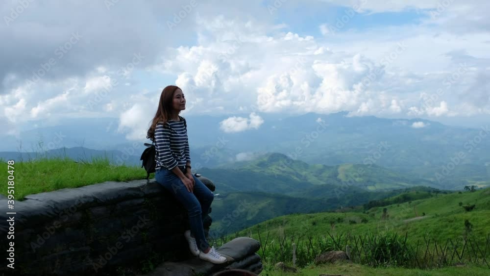 A female traveler sitting and looking at a beautiful mountain and nature view A female traveler sitting and looking at a beautiful mountain and nature view