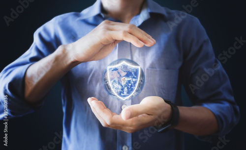 Businessman holding globe with protection shield icon. Saving earth, Energy saving and Security concept. Element of this image are furnished by NASA