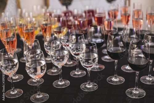 Line of alcohol setting on catering banquet table, bartender pouring beverages, row of different colored alcohol cocktails on a party, martini, vodka, and others on decorated banquet table event