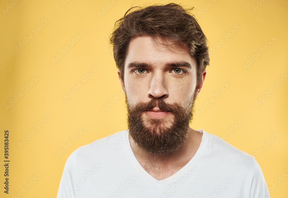 A man with a beard and mustache on a yellow background and a white T-shirt A man with a beard and mustache on a yellow background and a white T-shirt