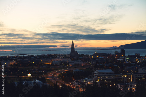 Beautiful night dusk view of Reykjavik, Iceland, aerial view with Hallgrimskirkja lutheran church, with scenery beyond the city, Esja mountain and Faxafloi bay © tsuguliev