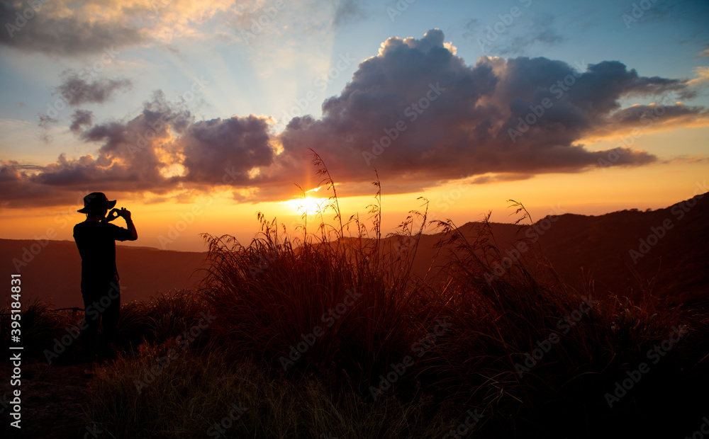 man taking photo of beautiful sunset on top mountain man taking photo of beautiful sunset on top mountain