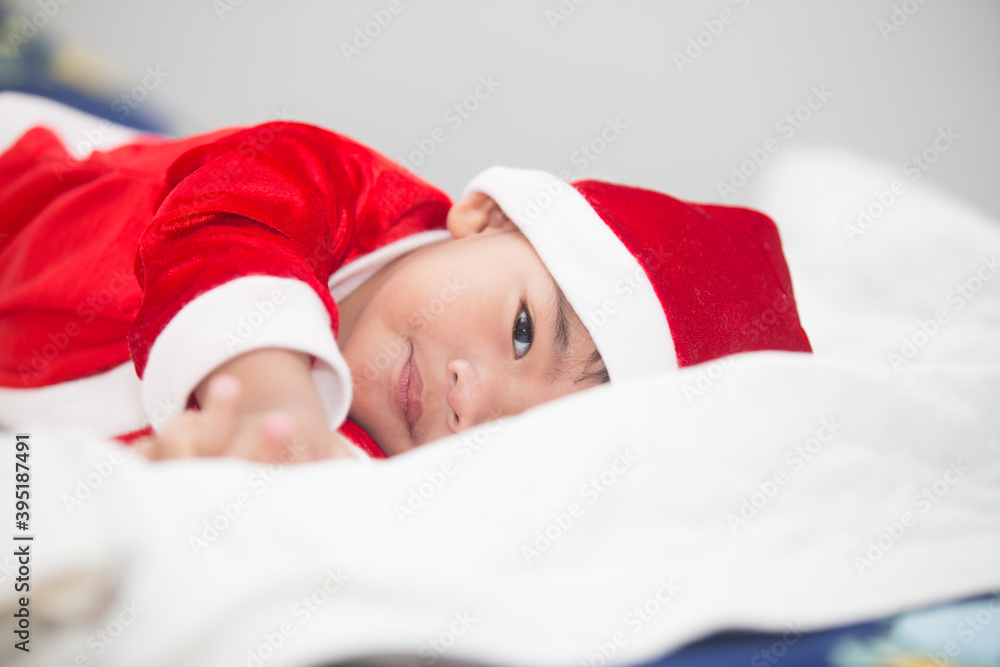 Thai boy in red Santa Claus outfit Was lying on the bed happily Happy Christmas Day. Thai boy in red Santa Claus outfit Was lying on the bed happily Happy Christmas Day.